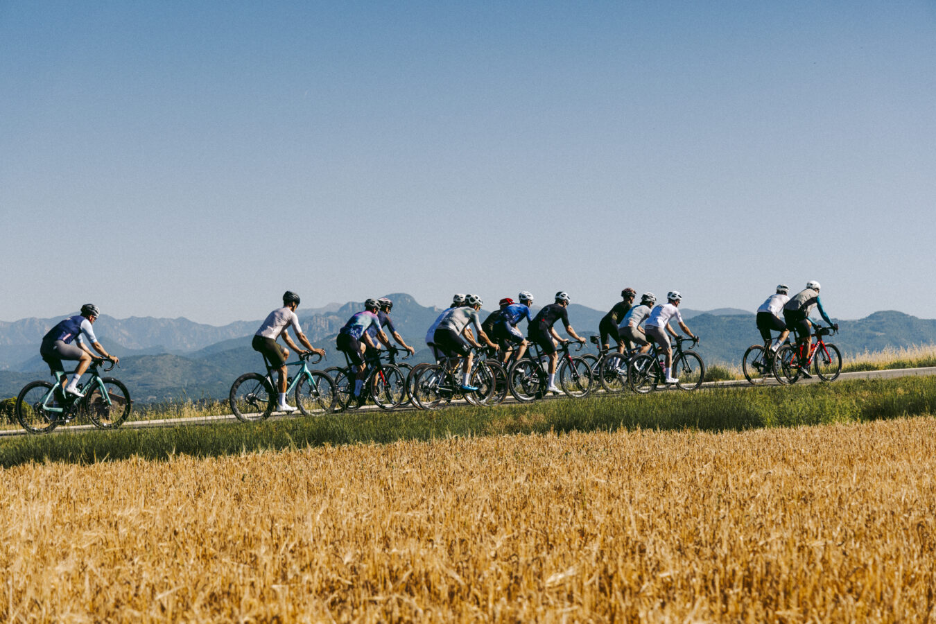 Grup de ciclistes pedalant entre camps i muntanyes durant l’estada a La Serra